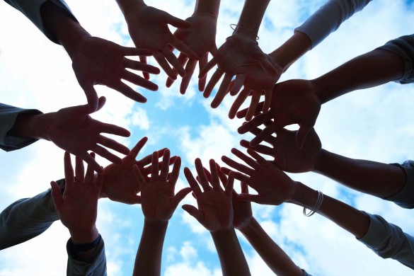 Group of  mixed hands showing unity with sky